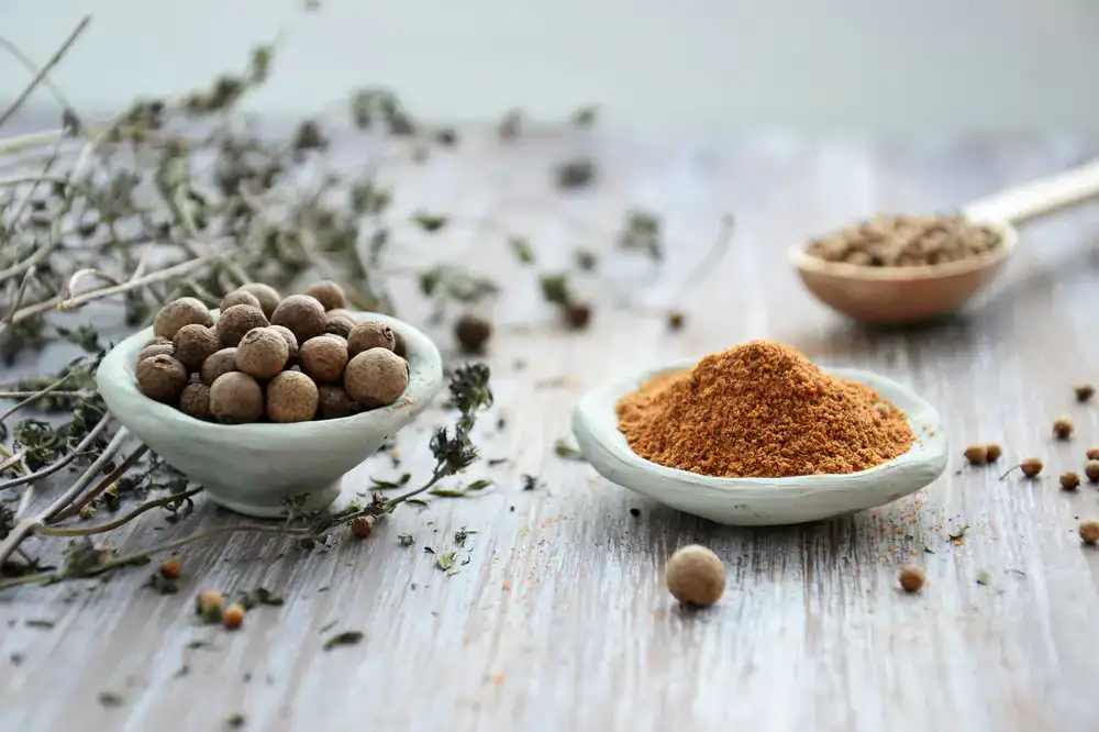 A collection of vibrant whole spices in small ceramic bowls