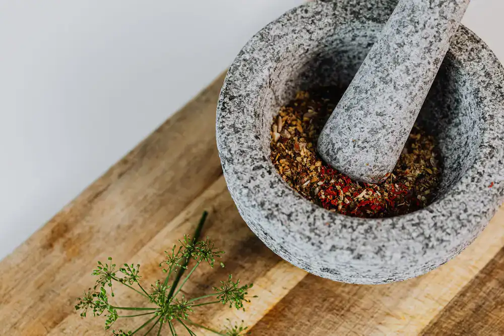 Close up of a wooden mortar and pestle mixing colorful spices